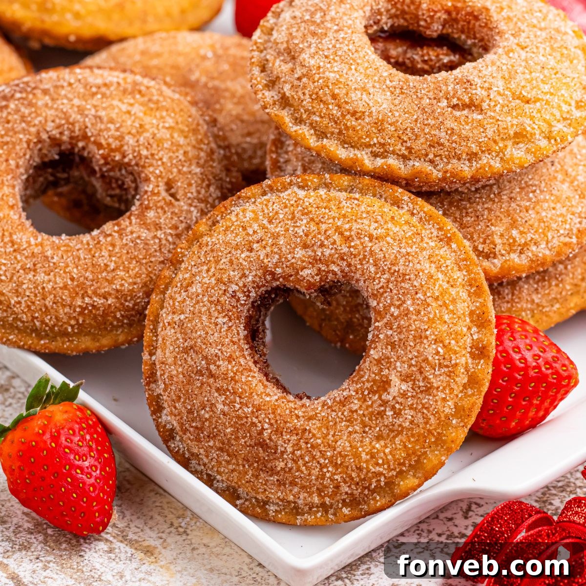 plate with Fried Strawberry Uncrustables that have been fried and rolled in sugar on plate with strawberries in front of plate 