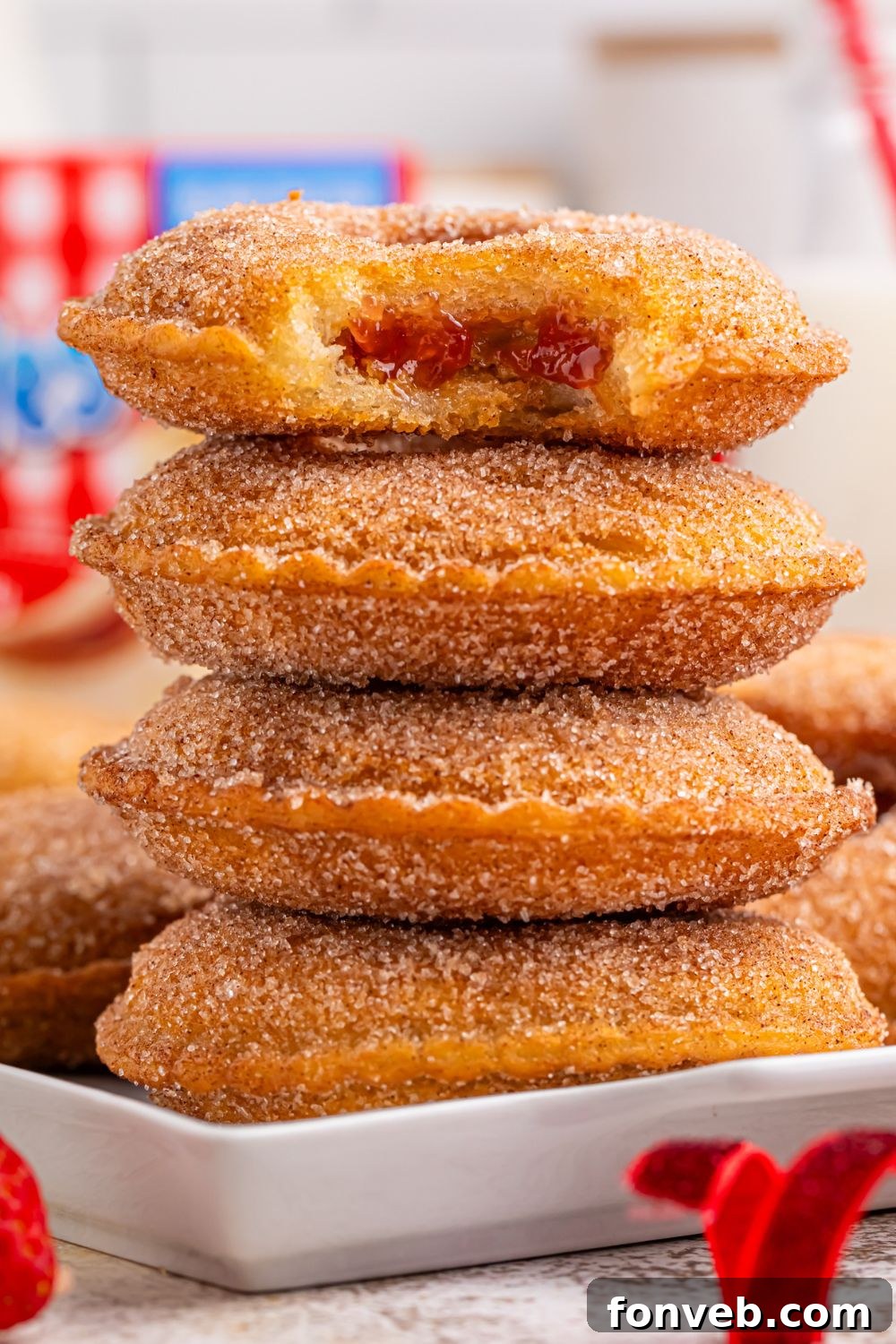 stack of Fried Strawberry Uncrustables on plate with top one that has a bite taken out of it 