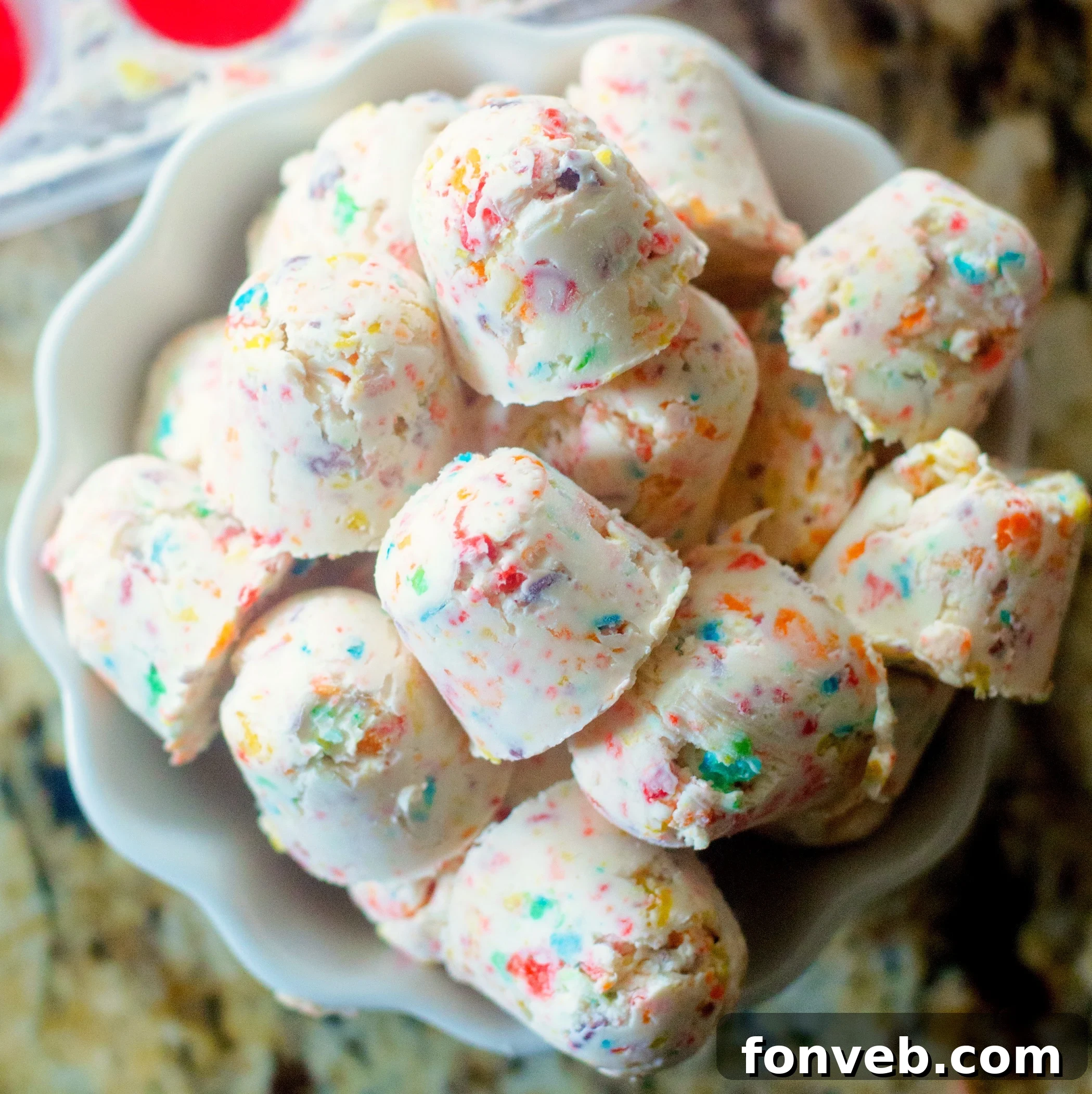 Close-up of a single Fruity Pebbles Cheesecake Bite, showcasing its colorful cereal topping and creamy texture.