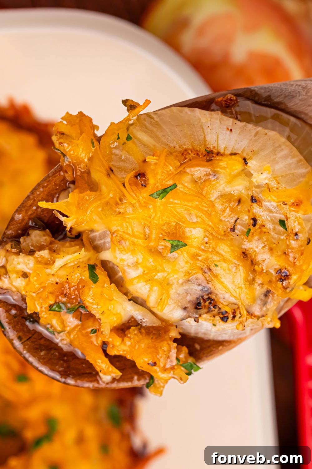 Cheesy Tennessee Onions being lifted out of a pan with a wooden spoon 