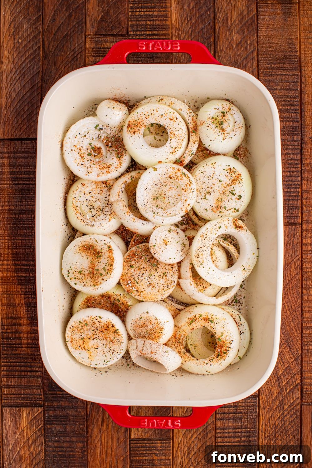 sliced onions in a casserole dish with seasonings on top