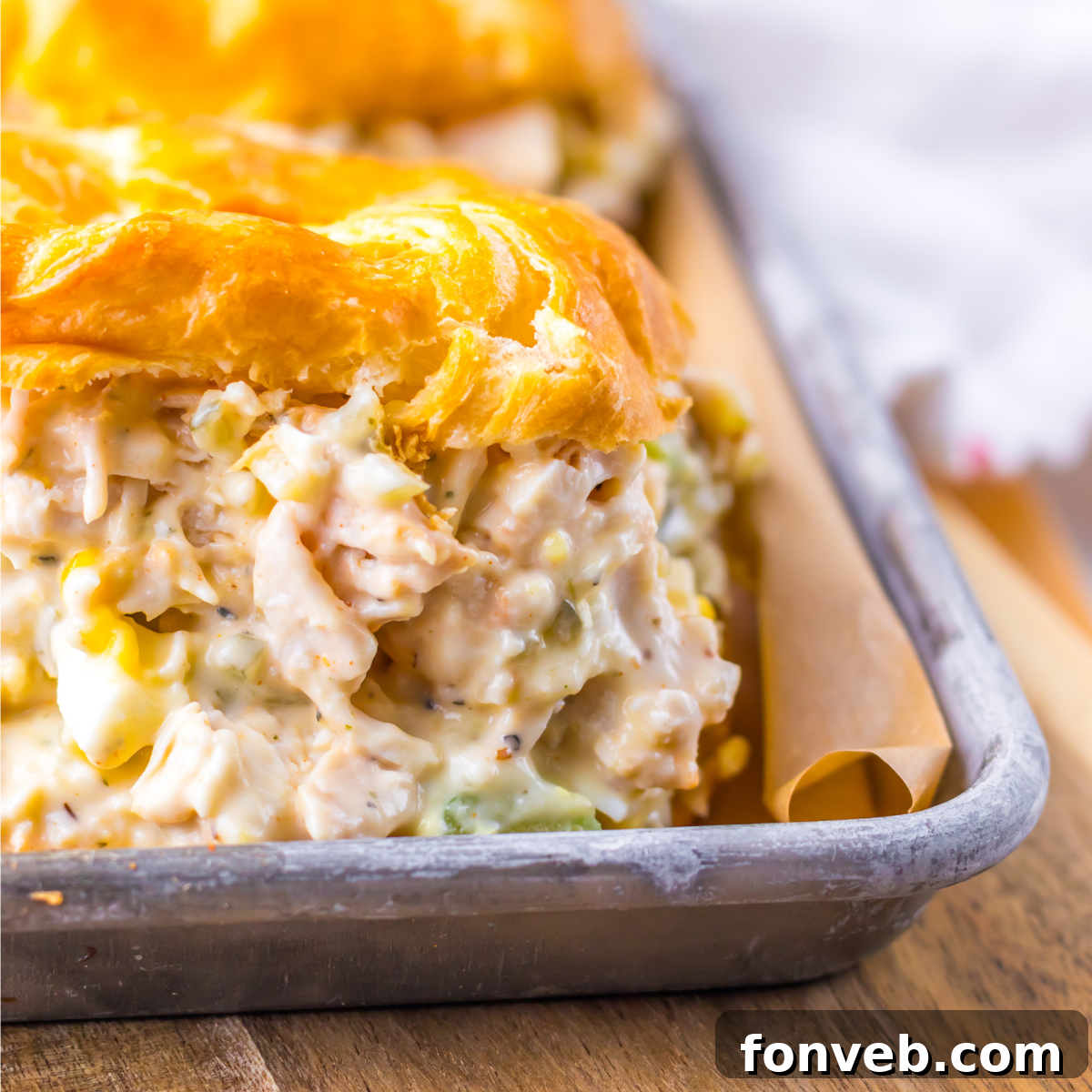 Close up shot of chicken salad on a white croissant on a tin tray.  