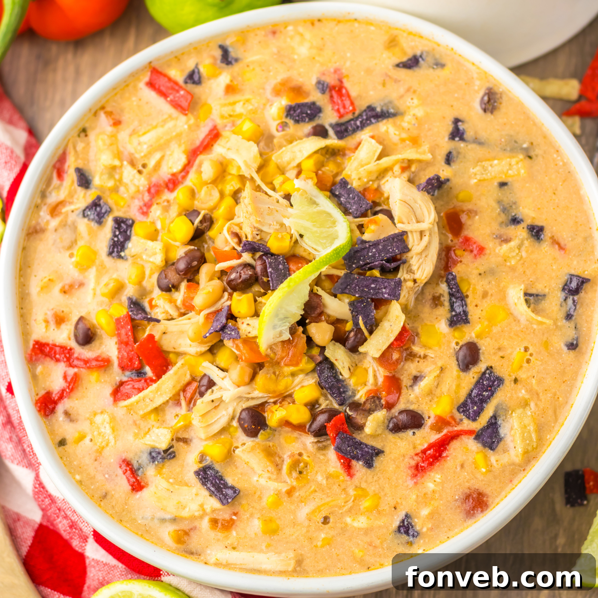 A close-up overhead view of Slow Cooker Tortilla Soup, richly adorned with toppings including vibrant corn kernels, savory black beans, and crispy tortilla chips.