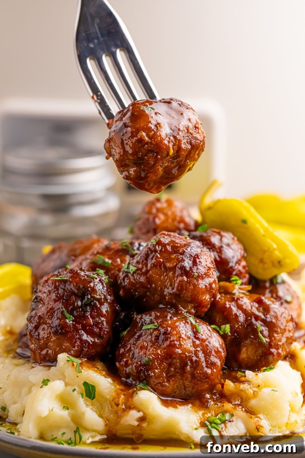 Crockpot Mississippi Meatballs on a plate with a fork lifting one off the plate 