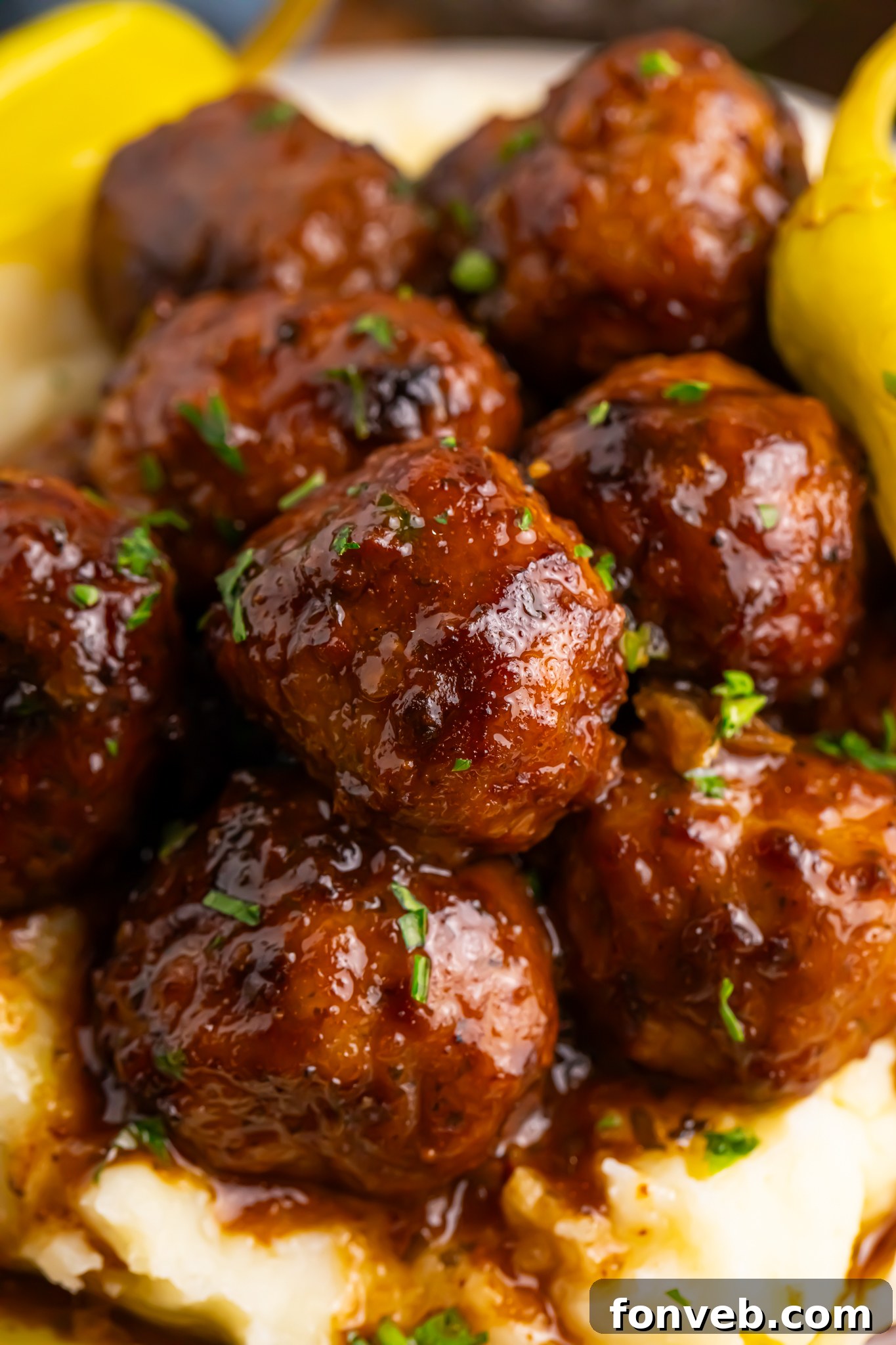Crockpot Mississippi Meatballs on a plate with mashed potatoes underneath a fork to the side on table 