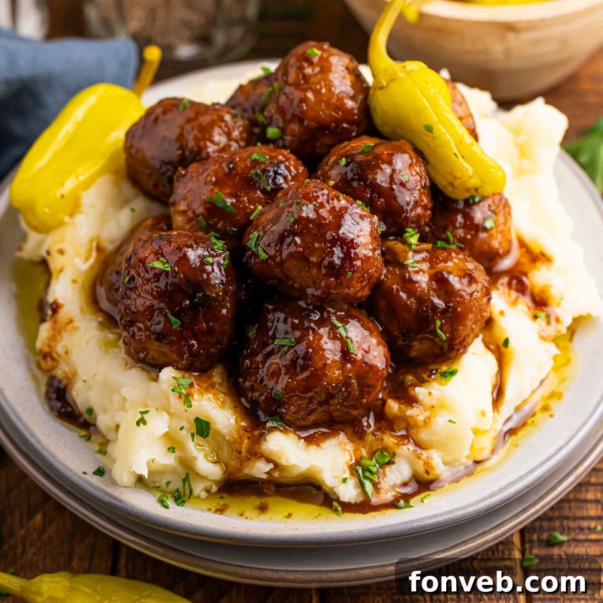 Crockpot Mississippi Meatballs on a plate with a bed of mashed potatoes underneath