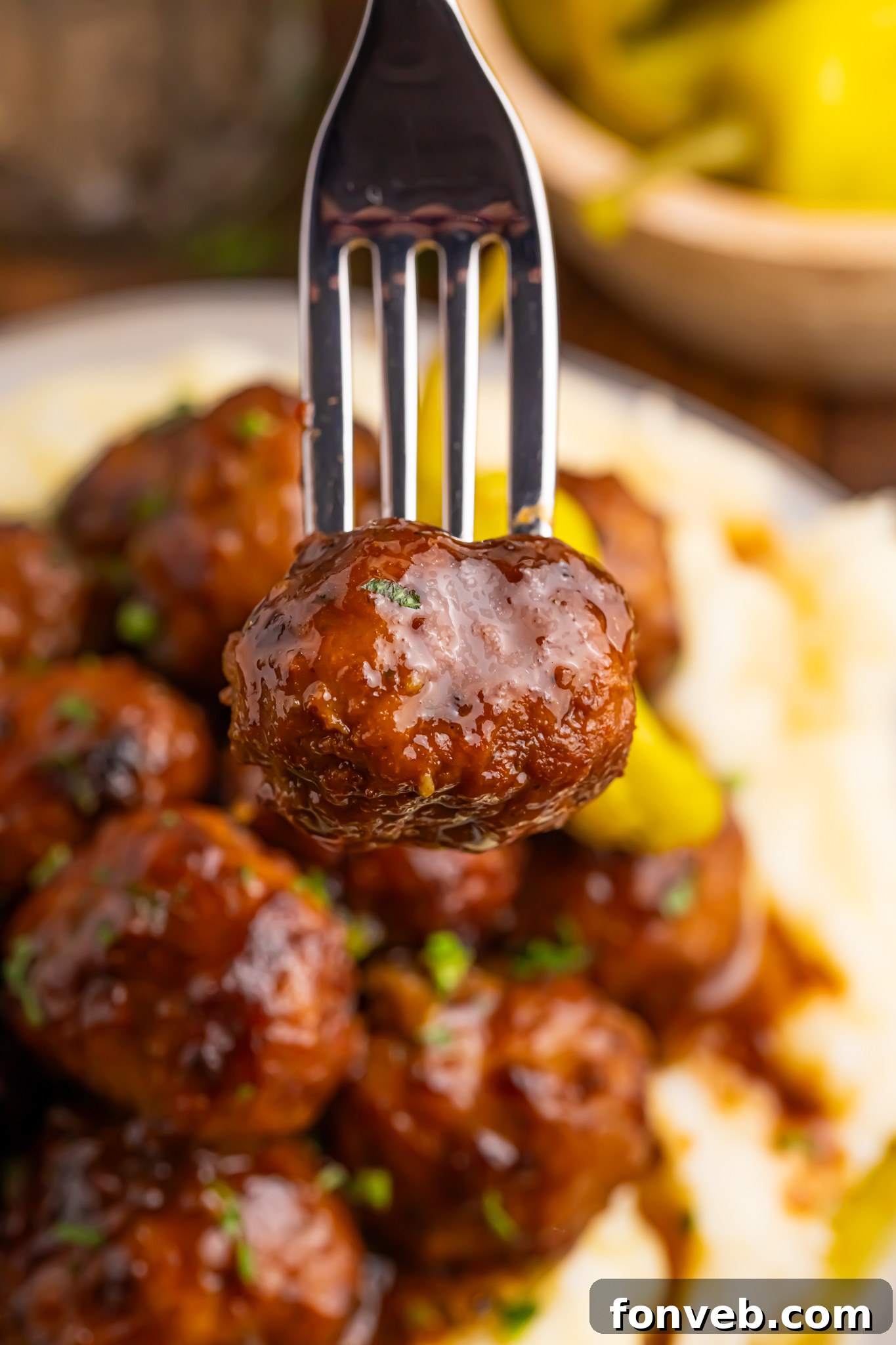 mashed potatoes and Crockpot Mississippi Meatballs on a plate and a fork with one meatball poked into it 