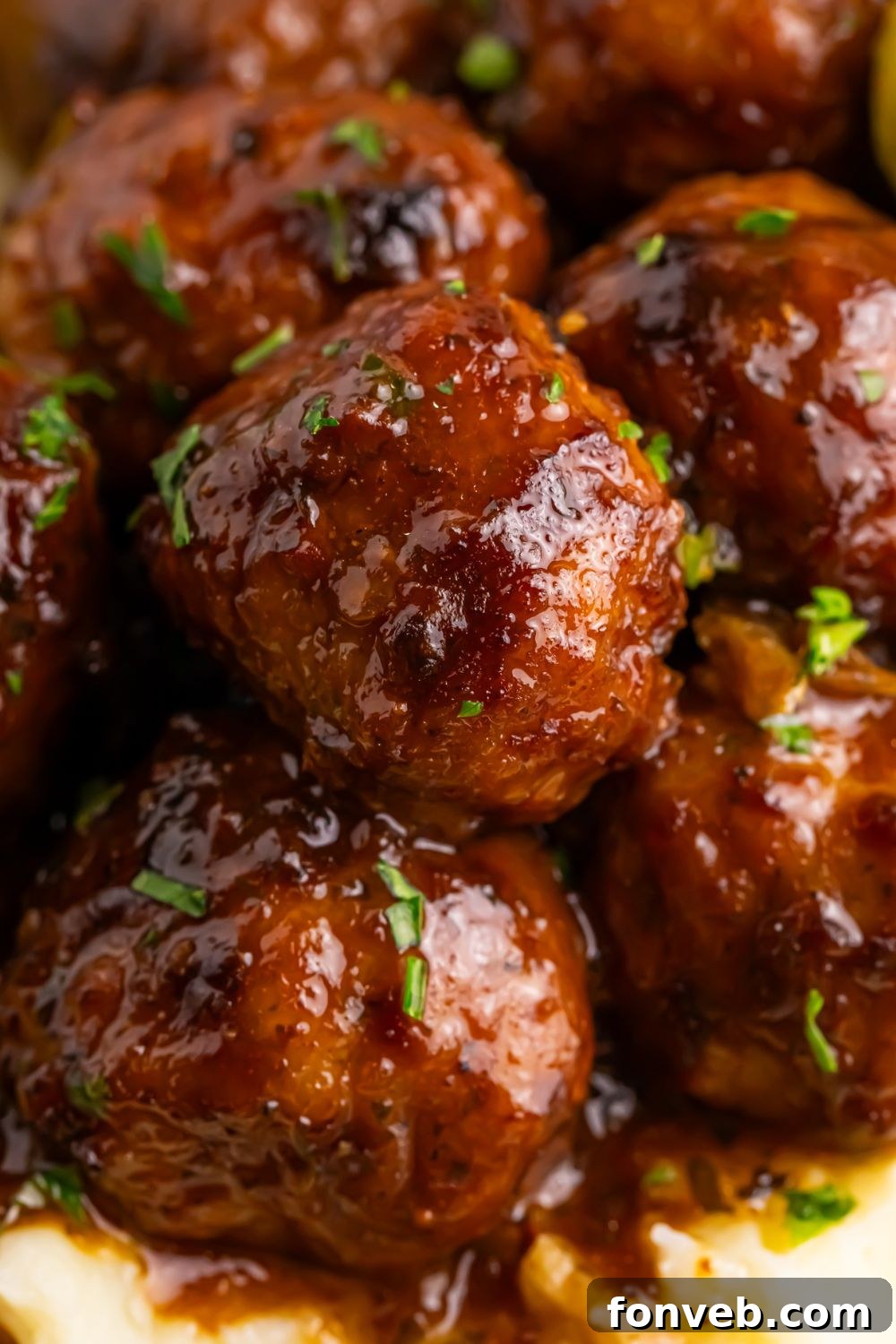 close up of a stack of Crockpot Mississippi Meatballs on a plate on table with garnish
