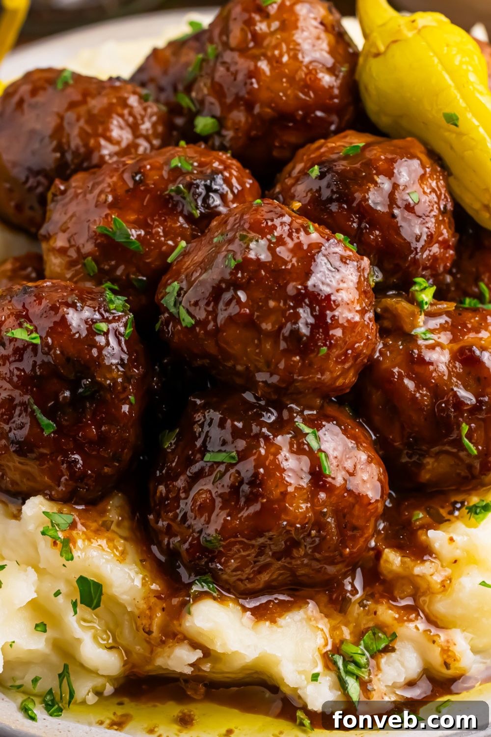 close up of Crockpot Mississippi Meatballs on plate with mashed potatoes under the meatballs 