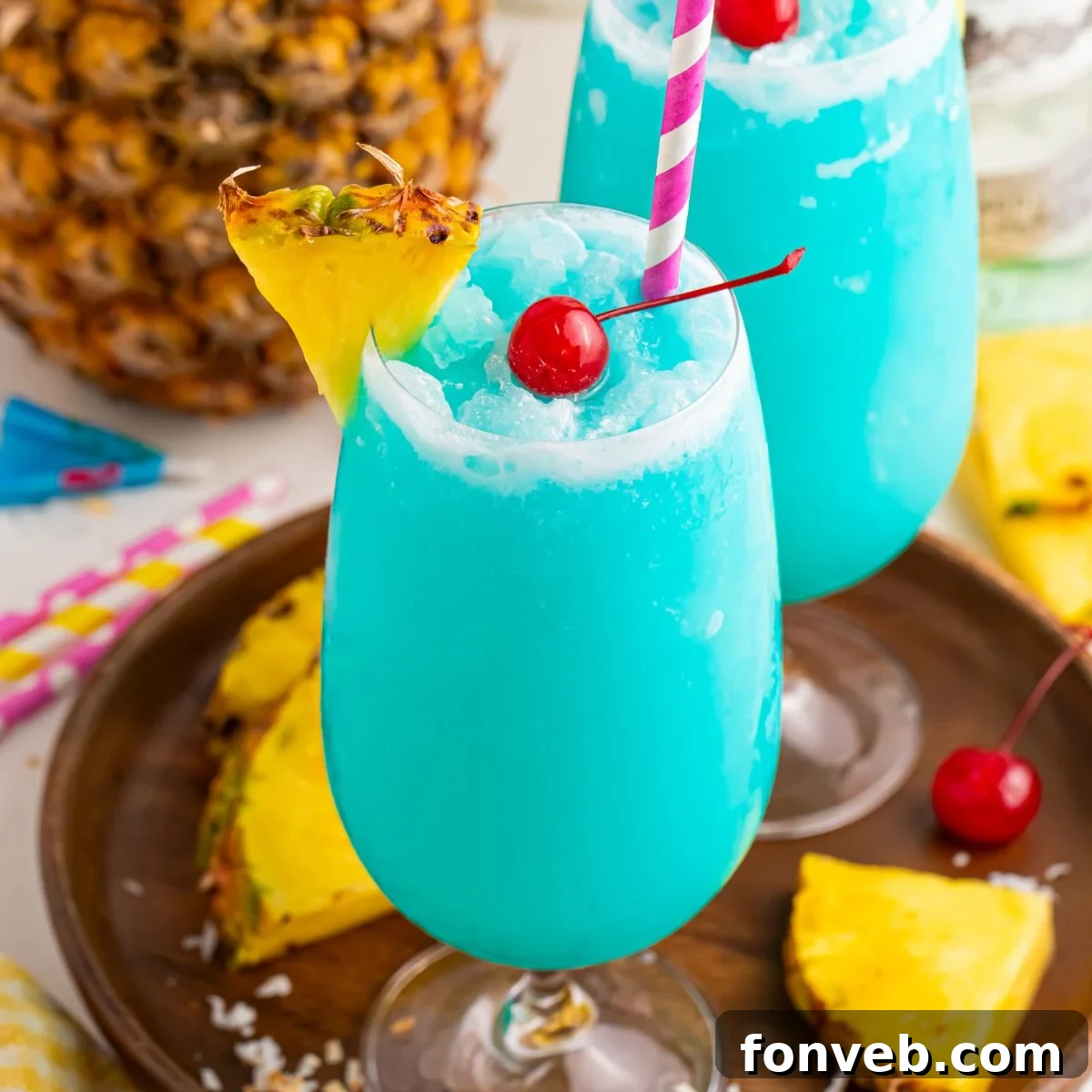 Frozen Blue Hawaiian Cocktails on serving tray with sliced pineapple and cherries around it on table 