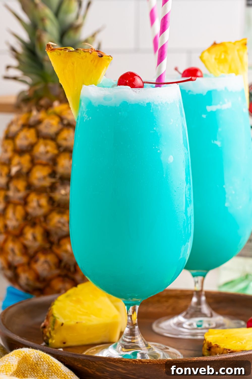 Frozen Blue Hawaiian Cocktails in glasses on table with pineapples around the table 