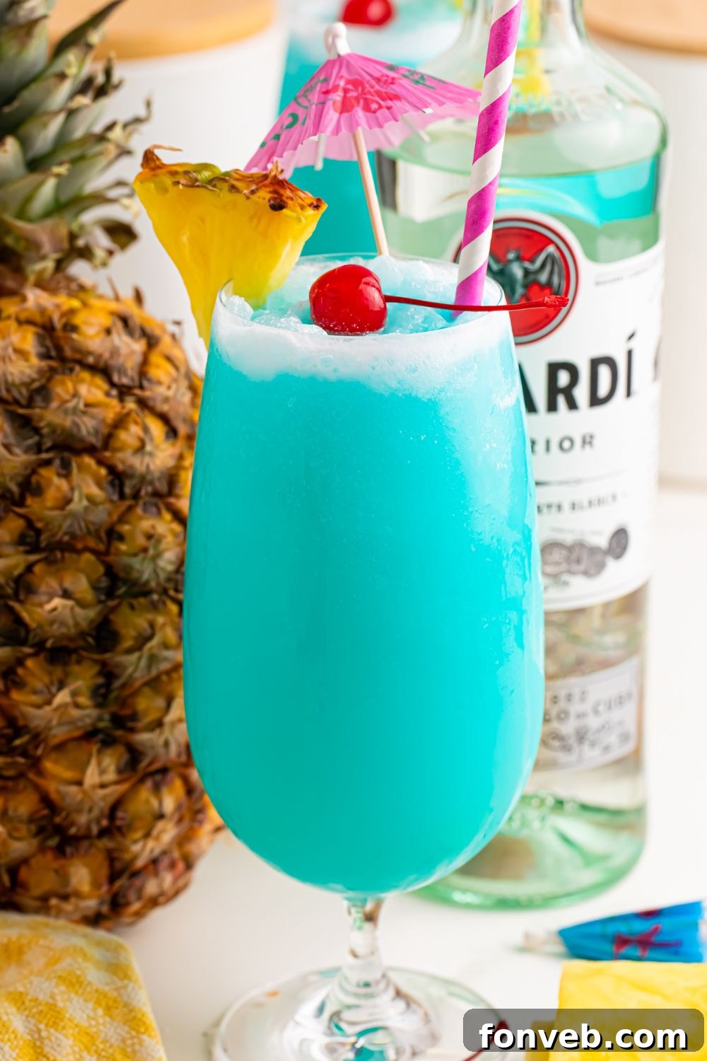 Frozen Blue Hawaiian Cocktail on table with rum and fruit around it on table