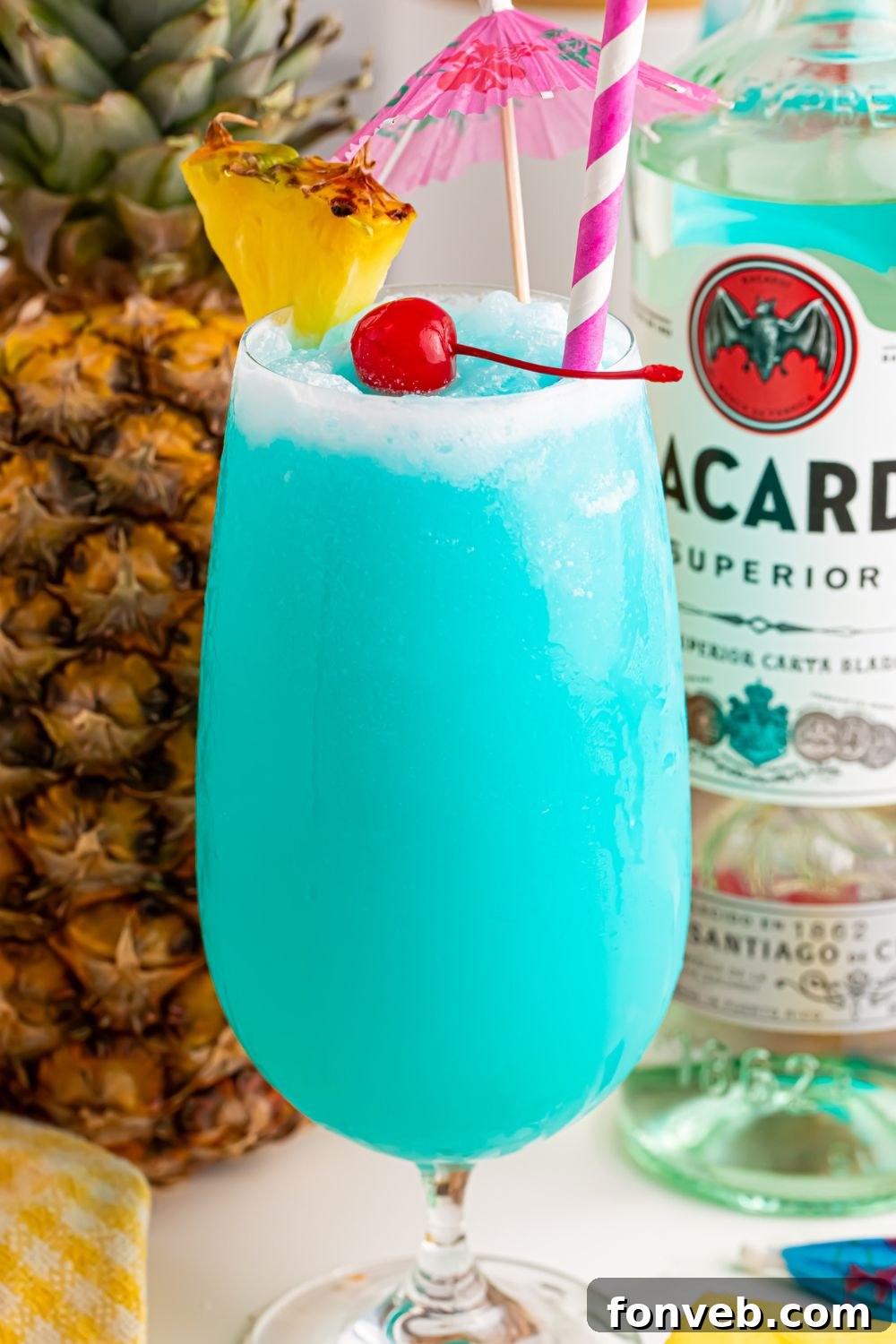 Frozen Blue Hawaiian Cocktail on table with a pineapple and bottle of rum behind it on table 