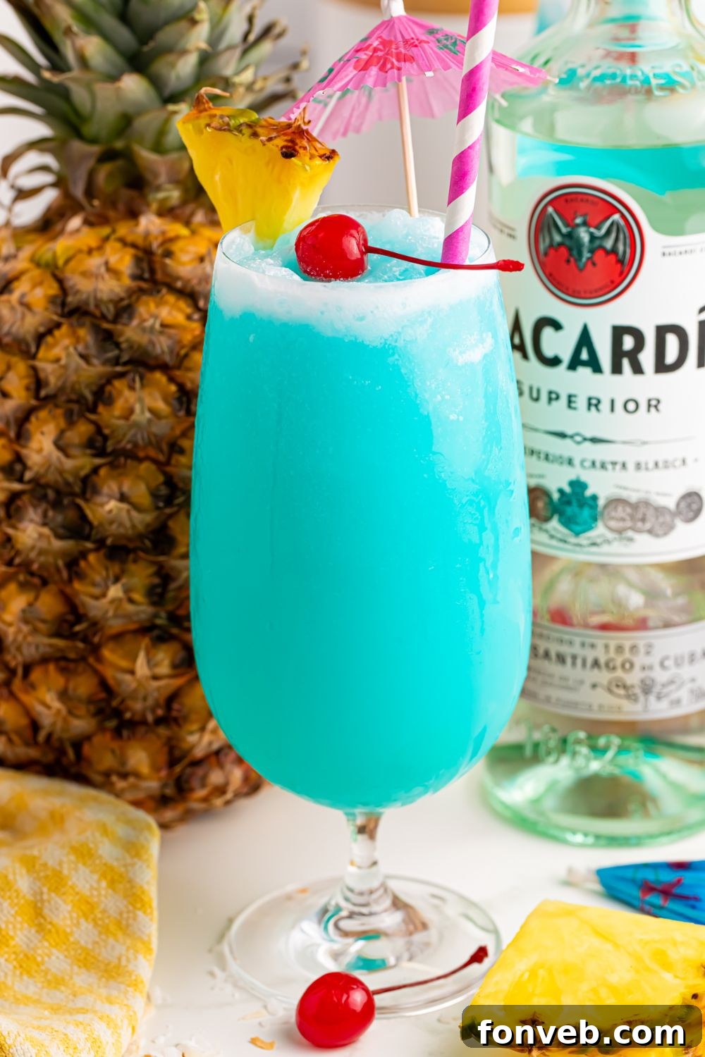 Frozen Blue Hawaiian Cocktail on table with bottle of rum and pineapple 