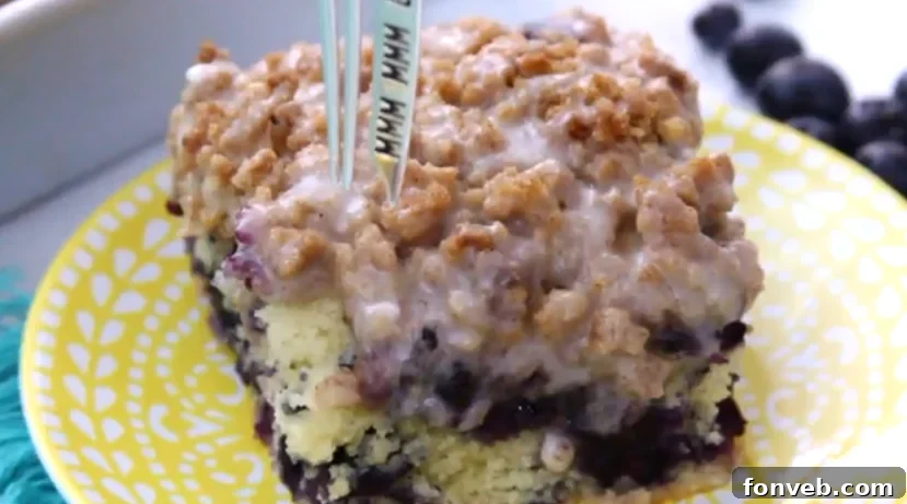 Close-up of a fork digging into a slice of Blueberry Muffin Buckle Cake