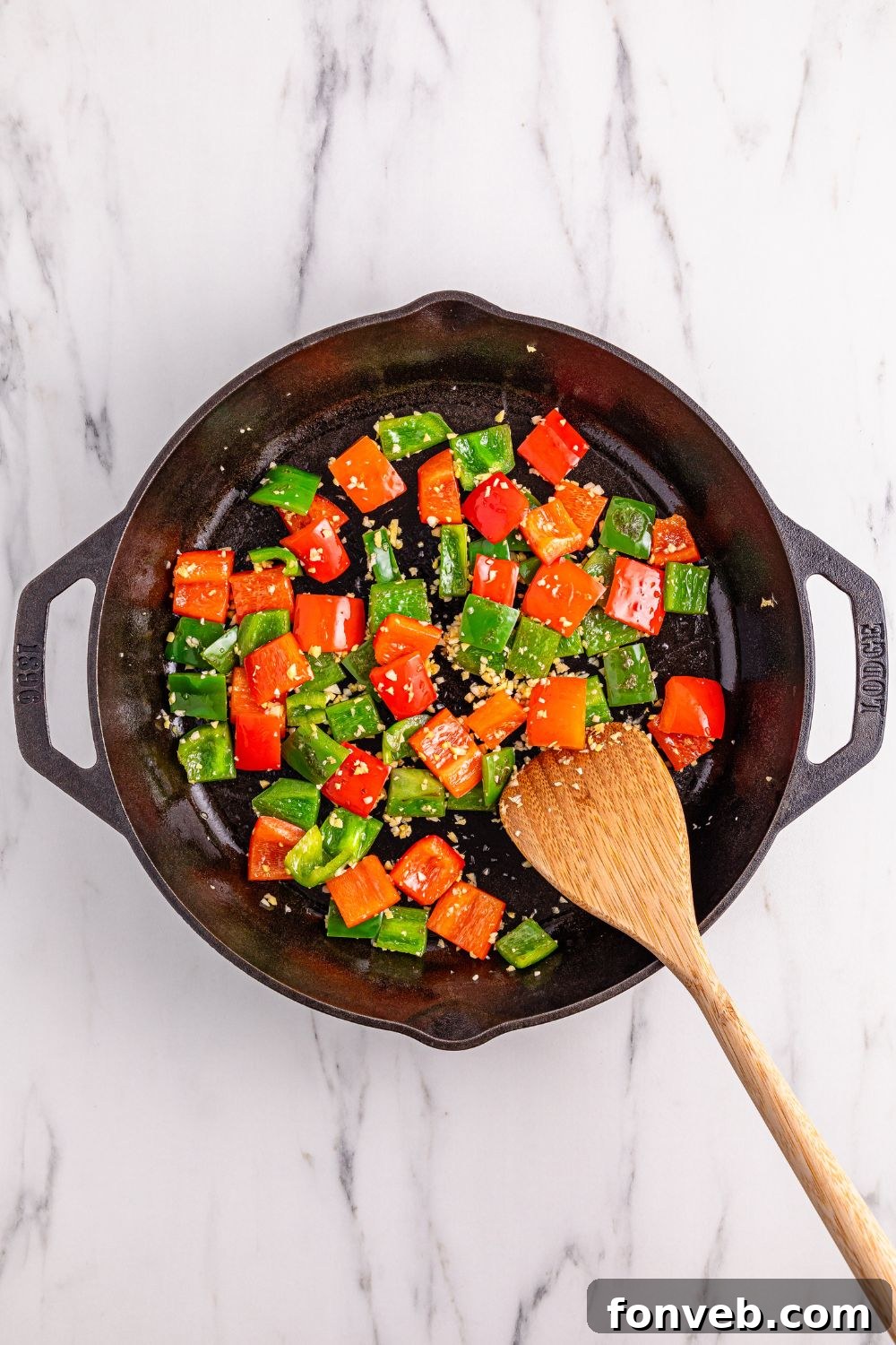 Sautéed bell peppers, garlic, and ginger in a cast iron skillet, forming the aromatic base for the Better Than Takeout Kung Pao Chicken.