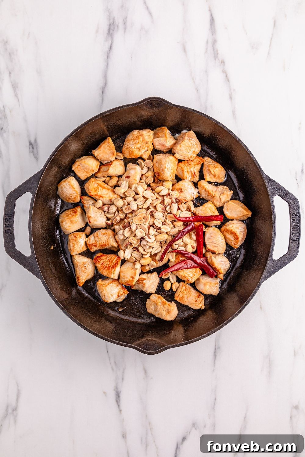 Chicken browning in a cast iron skillet, soon to be combined with the rich sauce and other ingredients for the homemade Kung Pao Chicken.