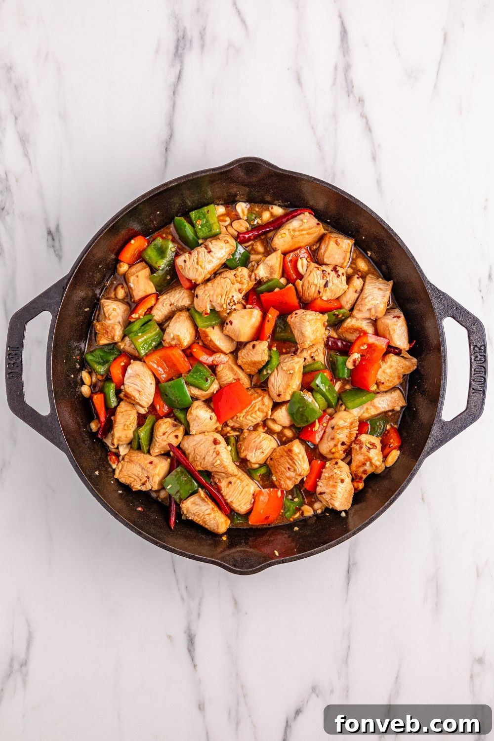 The delicious stir-fry, Better Than Takeout Kung Pao Chicken, simmering in a cast iron skillet on the stovetop, radiating warmth and flavor.