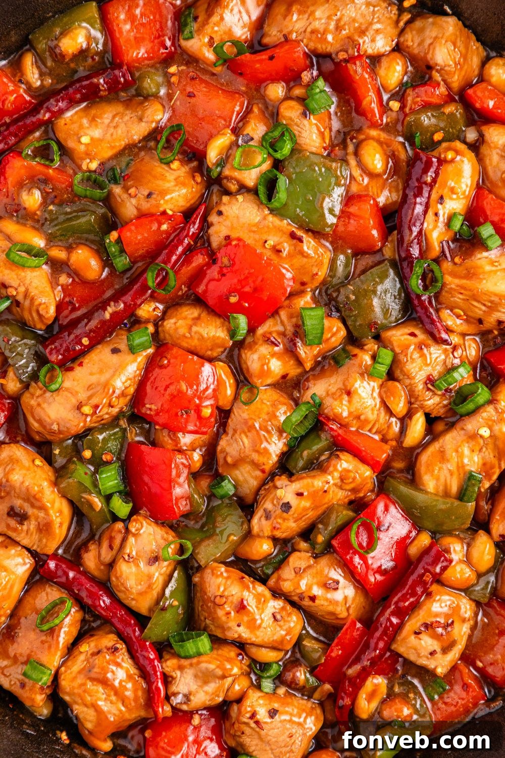 A close-up view of Better Than Takeout Kung Pao Chicken in a pan, showing the meat and vegetables beautifully coated in the rich, glossy sauce.