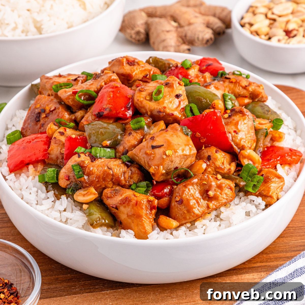 A serving of Better Than Takeout Kung Pao Chicken elegantly plated in a bowl atop a bed of fluffy white rice, highlighting its saucy appeal.