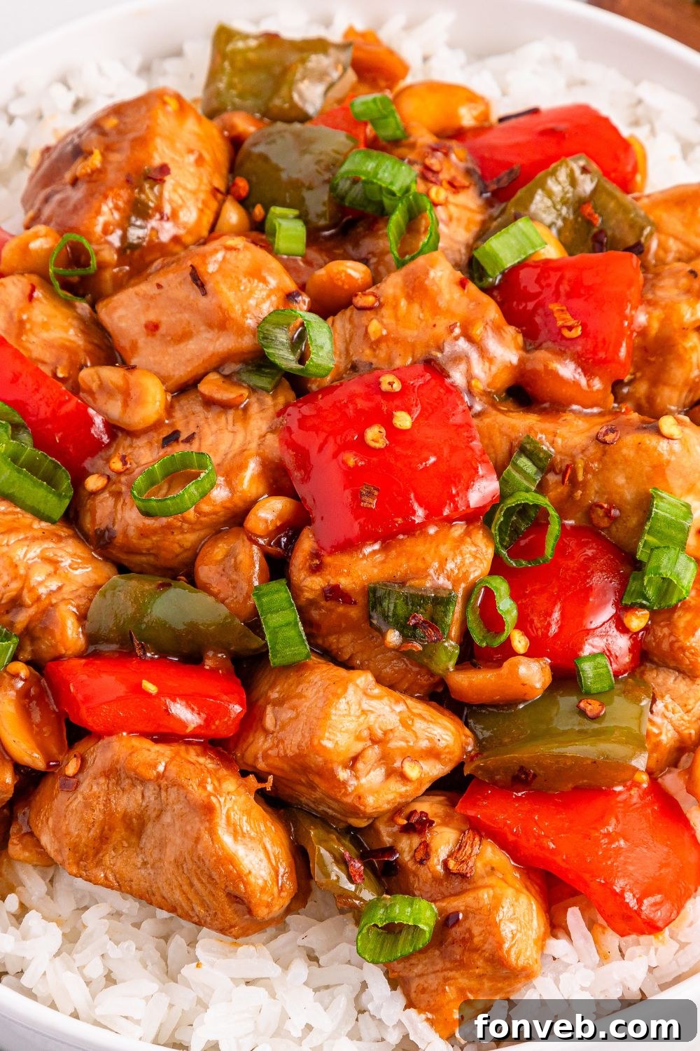 Better Than Takeout Kung Pao Chicken served on a plate with rice, showing a close-up of the chicken and vegetables coated in the rich sauce.