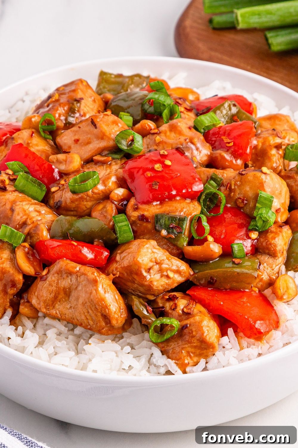 An enticing bowl of Better Than Takeout Kung Pao Chicken served over fluffy white rice, showcasing the perfectly coated chicken and vegetables.