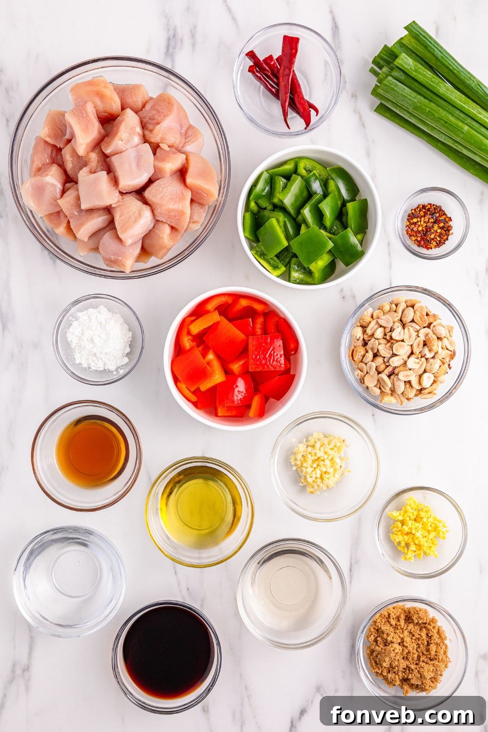 A collection of fresh ingredients, including bell peppers, peanuts, and chili peppers, neatly arranged in bowls for making homemade Kung Pao Chicken.