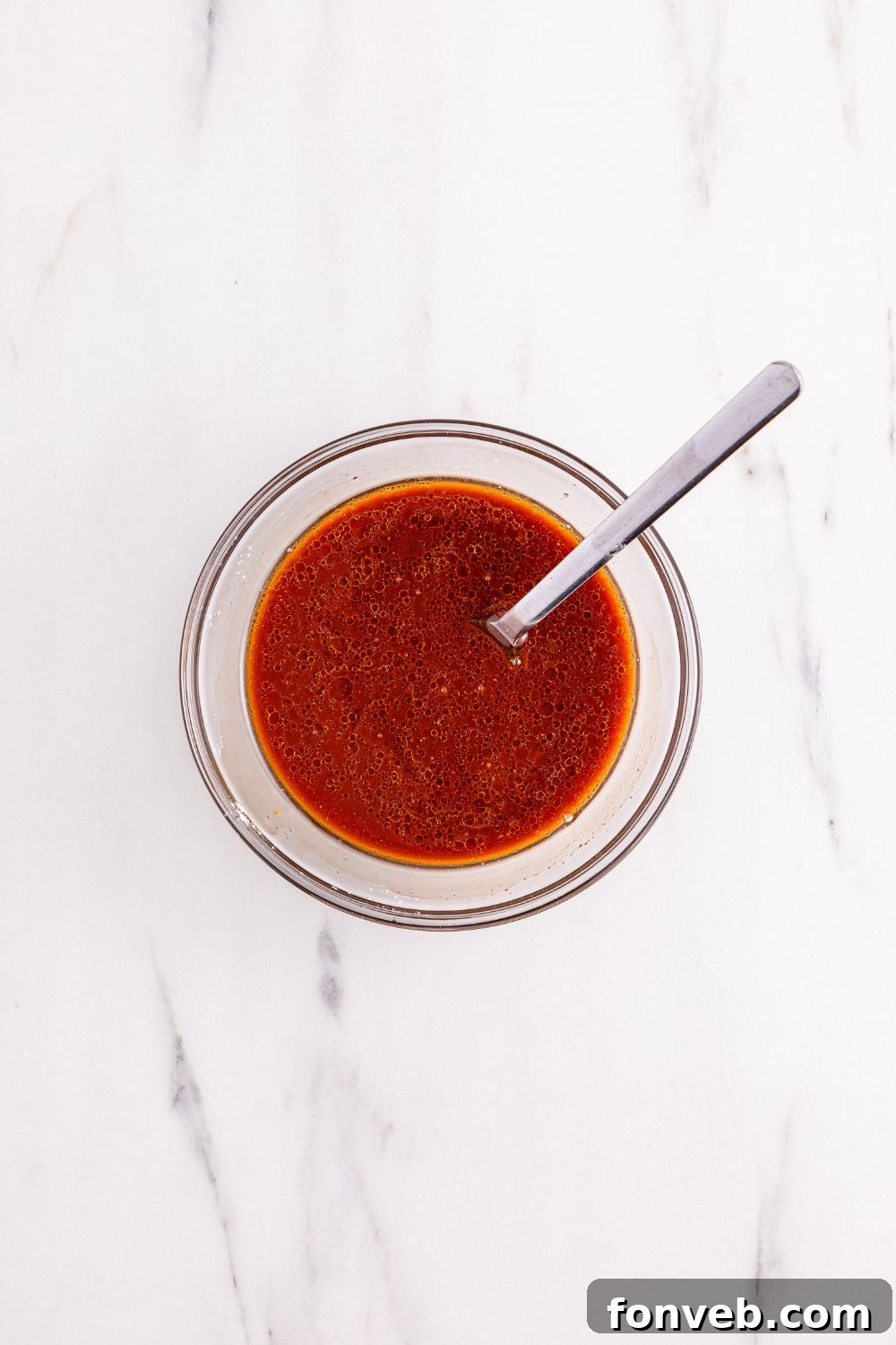 The Kung Pao Chicken sauce, perfectly mixed and ready, sits in a bowl with a spoon, highlighting its ideal consistency.