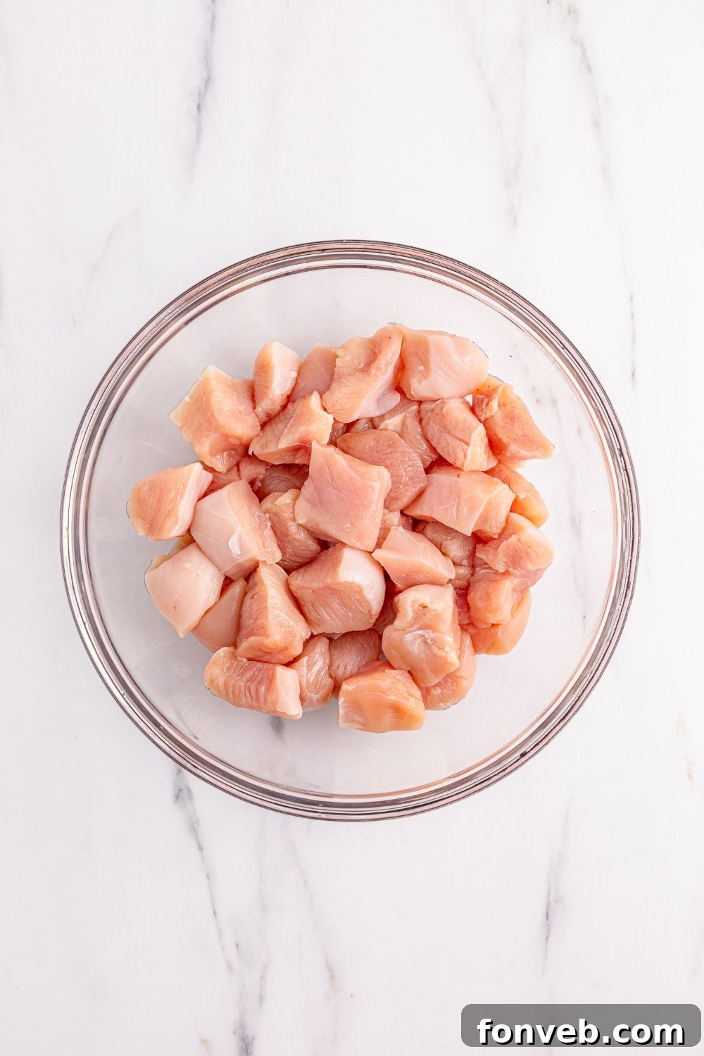 Cubed raw chicken in a bowl, meticulously prepared and ready for marinating to create the Better Than Takeout Kung Pao Chicken.