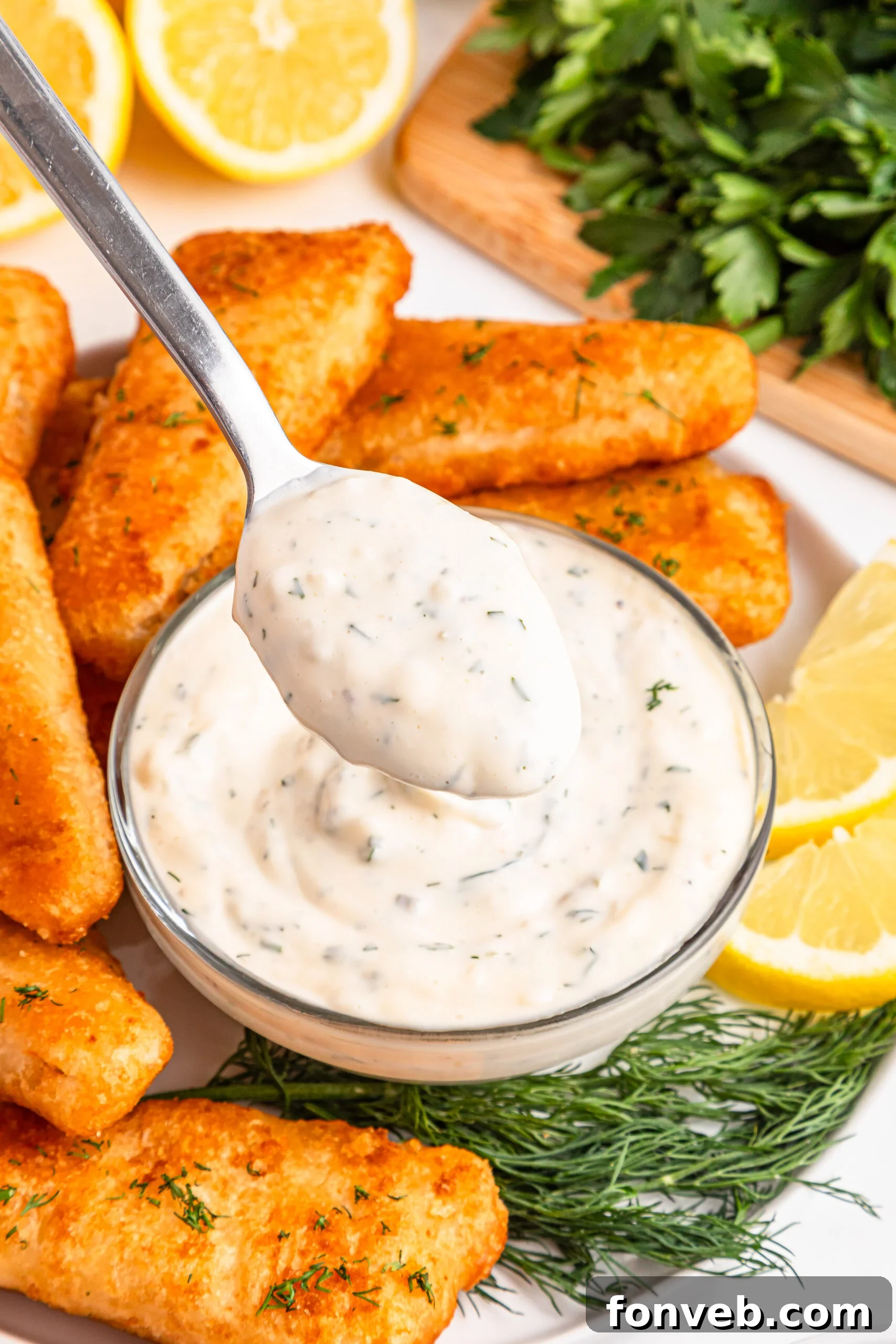 Effortless Homemade Tartar Sauce Beats Store Bought 2 A small white bowl filled with creamy homemade tartar sauce, with a spoon lifting some up, showcasing its smooth texture and flecks of herbs.