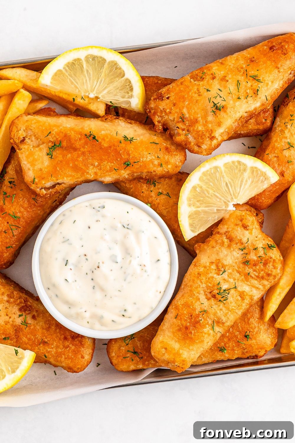 Effortless Homemade Tartar Sauce Beats Store Bought 14 A bowl of Easy Homemade Tartar Sauce positioned next to a piece of perfectly cooked fish, illustrating a classic pairing.