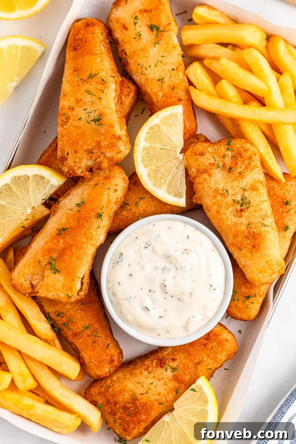 Effortless Homemade Tartar Sauce Beats Store Bought 7 A rustic tray laden with golden French fries, perfectly battered fish fillets, bright lemon wedges, and a inviting bowl of homemade tartar sauce, ready to be enjoyed.
