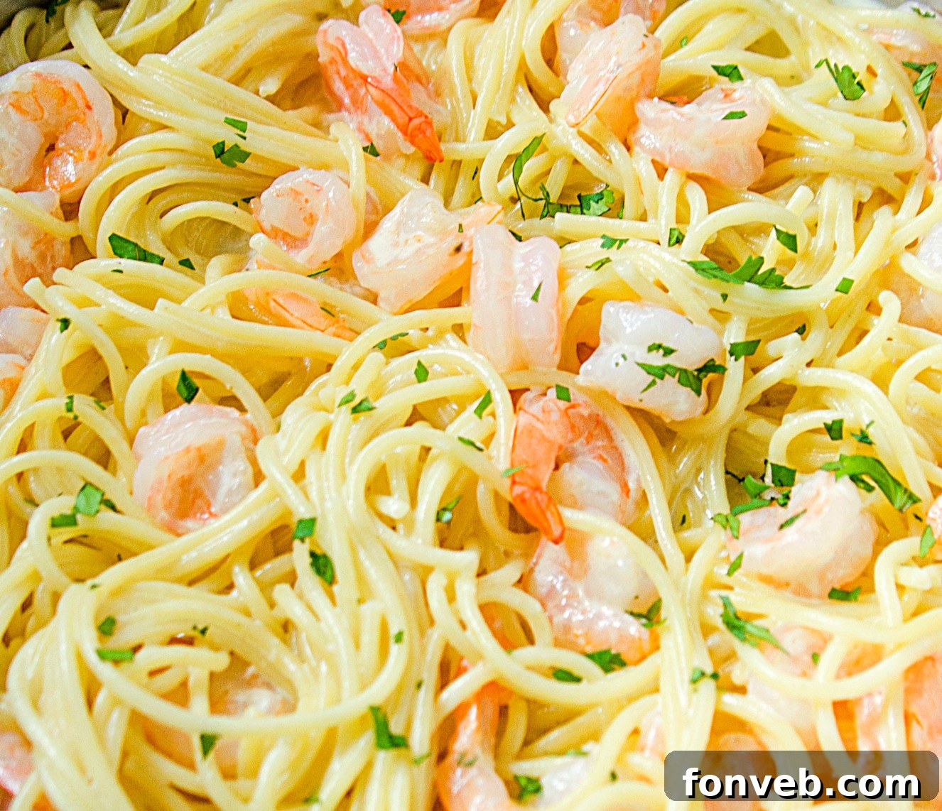 A serving of Four Cheese Garlic Shrimp Pasta with a fork lifting some spaghetti, showing off the melted cheese.