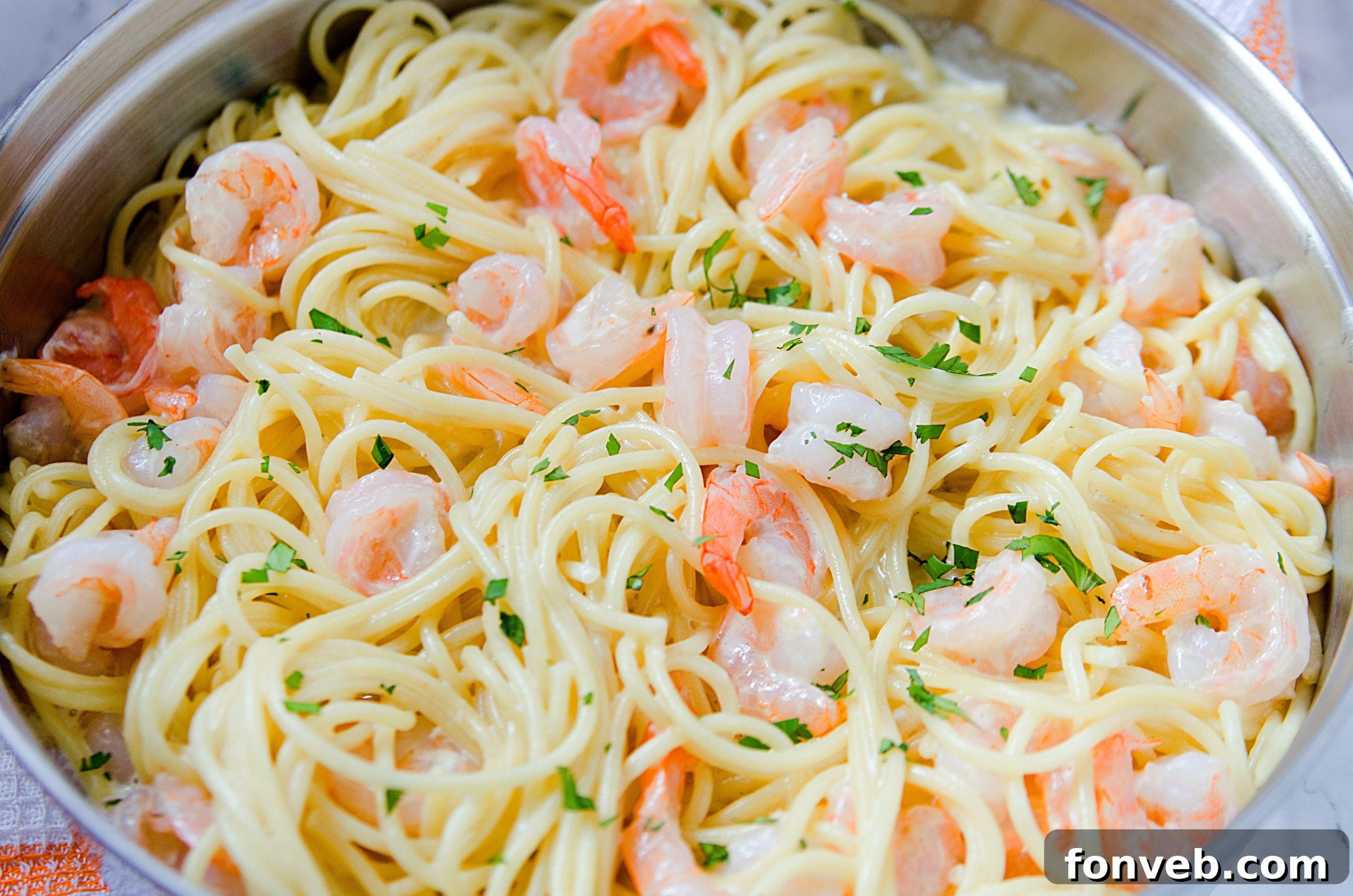 Overhead shot of the finished Four Cheese Garlic Shrimp Pasta in a serving dish, garnished with fresh herbs.