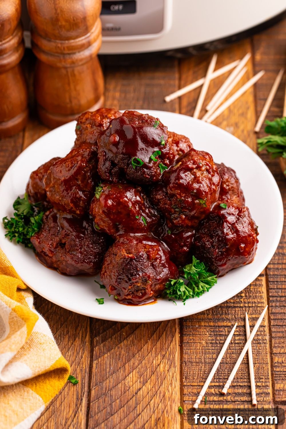 Crockpot Homemade BBQ Meatballs sitting on a plate with toothpicks around table and salt and pepper shaker to side 