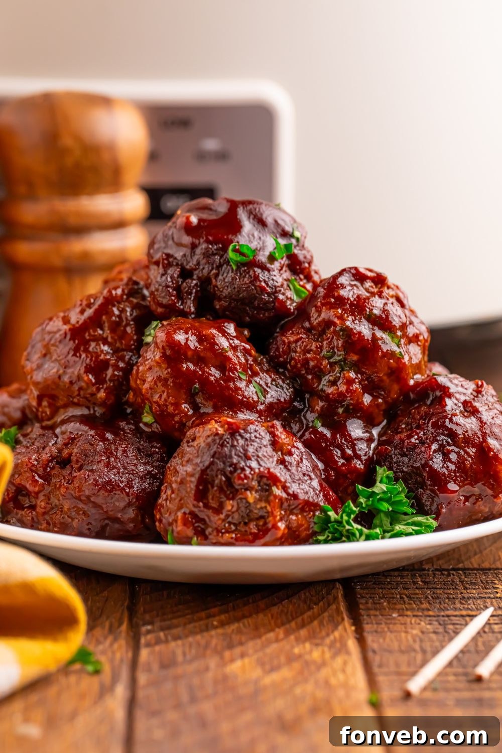 Crockpot Homemade BBQ Meatballs stacked on table with parsley on side and toothpicks to side