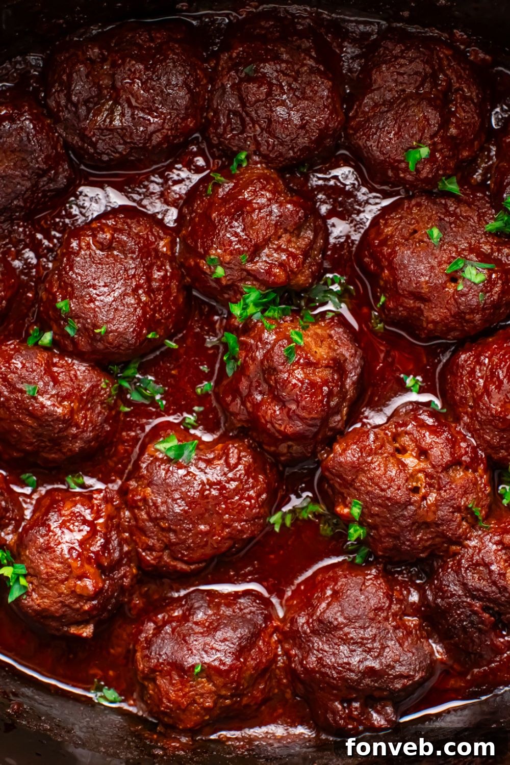 CrockPot full of meatballs in it topped with parsley 