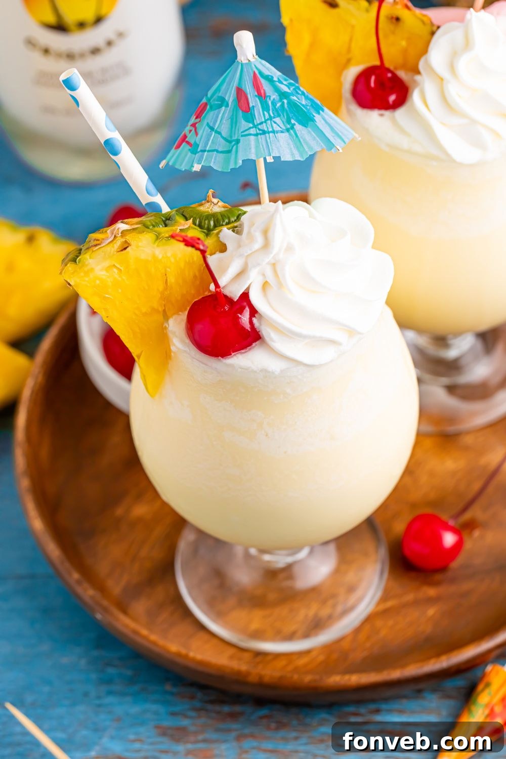 Creamy Frozen Malibu Piña Colada Delight 11 Frozen Malibu Piña Colada on table with pineapple wedge and umbrella