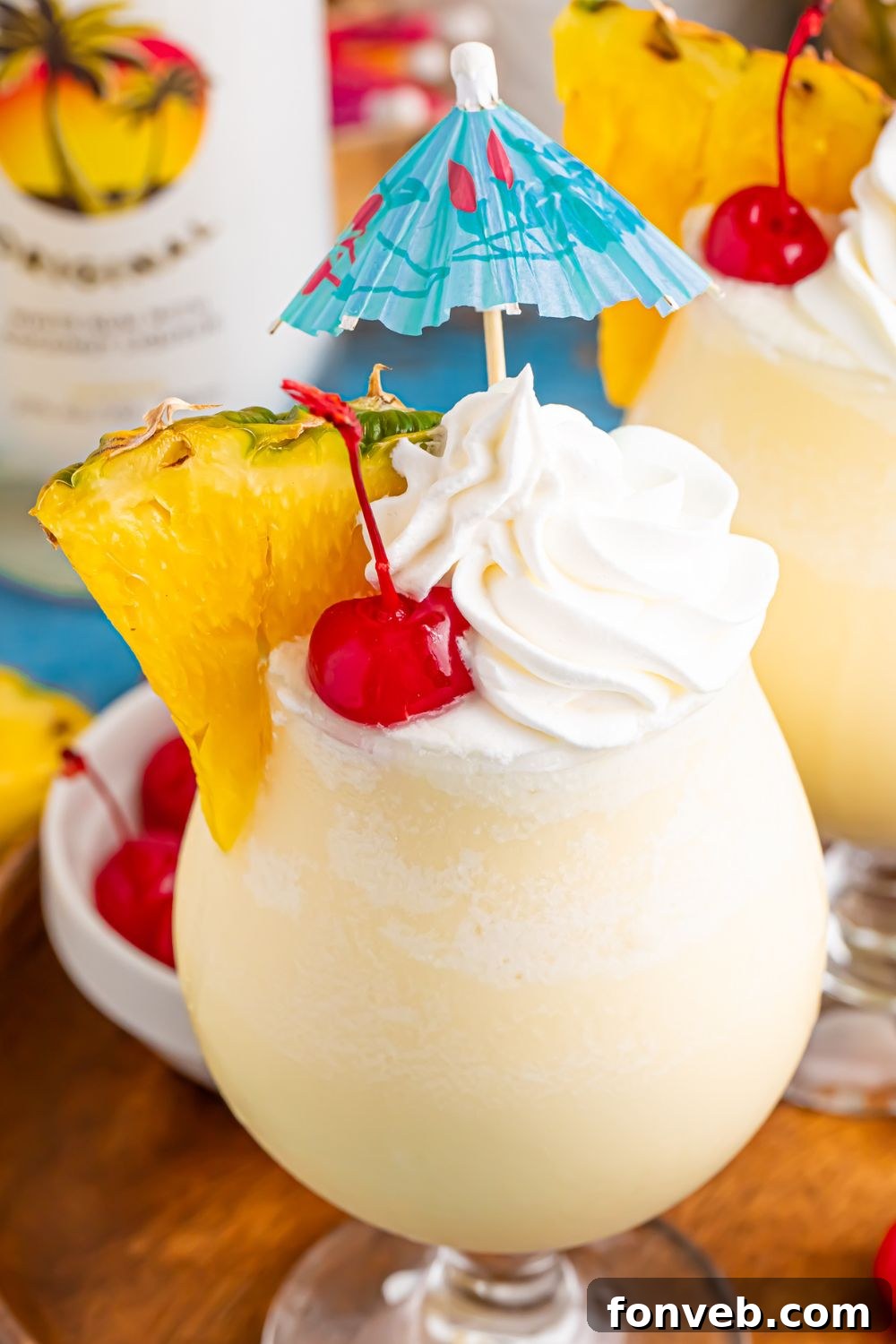 Creamy Frozen Malibu Piña Colada Delight 13 Frozen Malibu Piña Colada drinks on table with whipped cream, umbrella, and pineapple wedge in drink