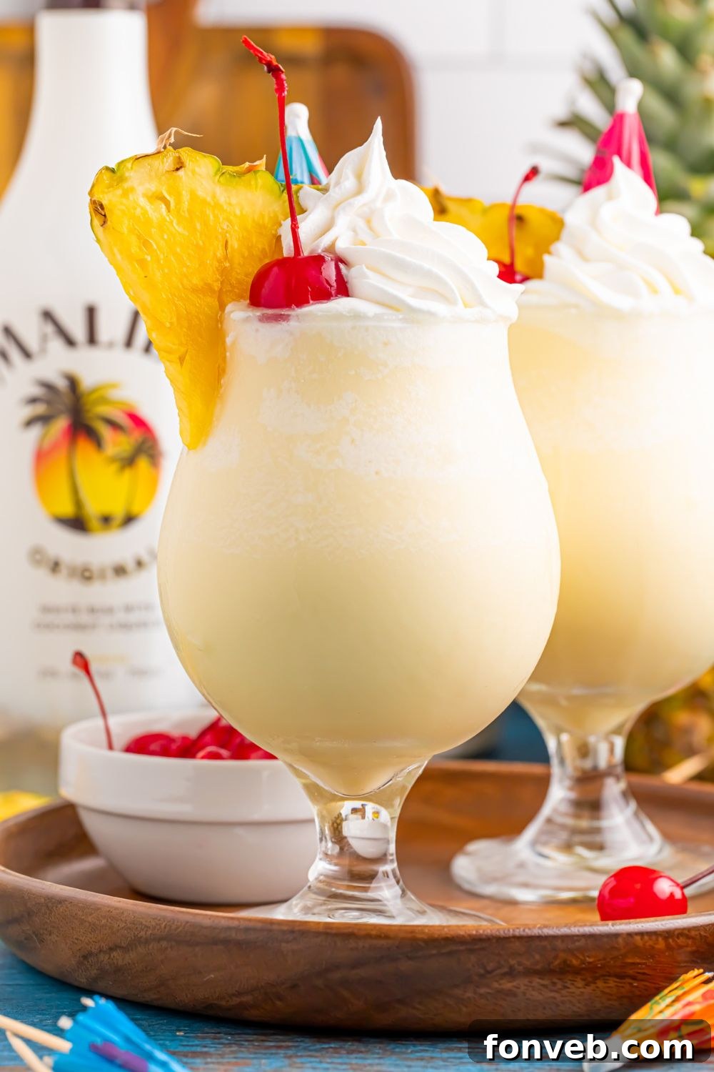 Creamy Frozen Malibu Piña Colada Delight 17 two Frozen Malibu Piña Coladas sitting on a tray with bowl of cherries, and a bottle of Malibu rum to the side
