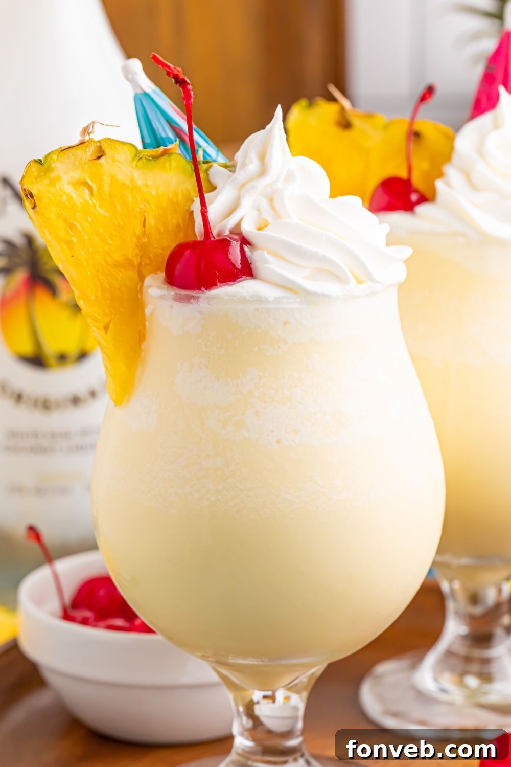 Creamy Frozen Malibu Piña Colada Delight 18 bottle of Frozen Malibu Piña Coladas sitting on a serving tray with rum and pineapple behind it on table
