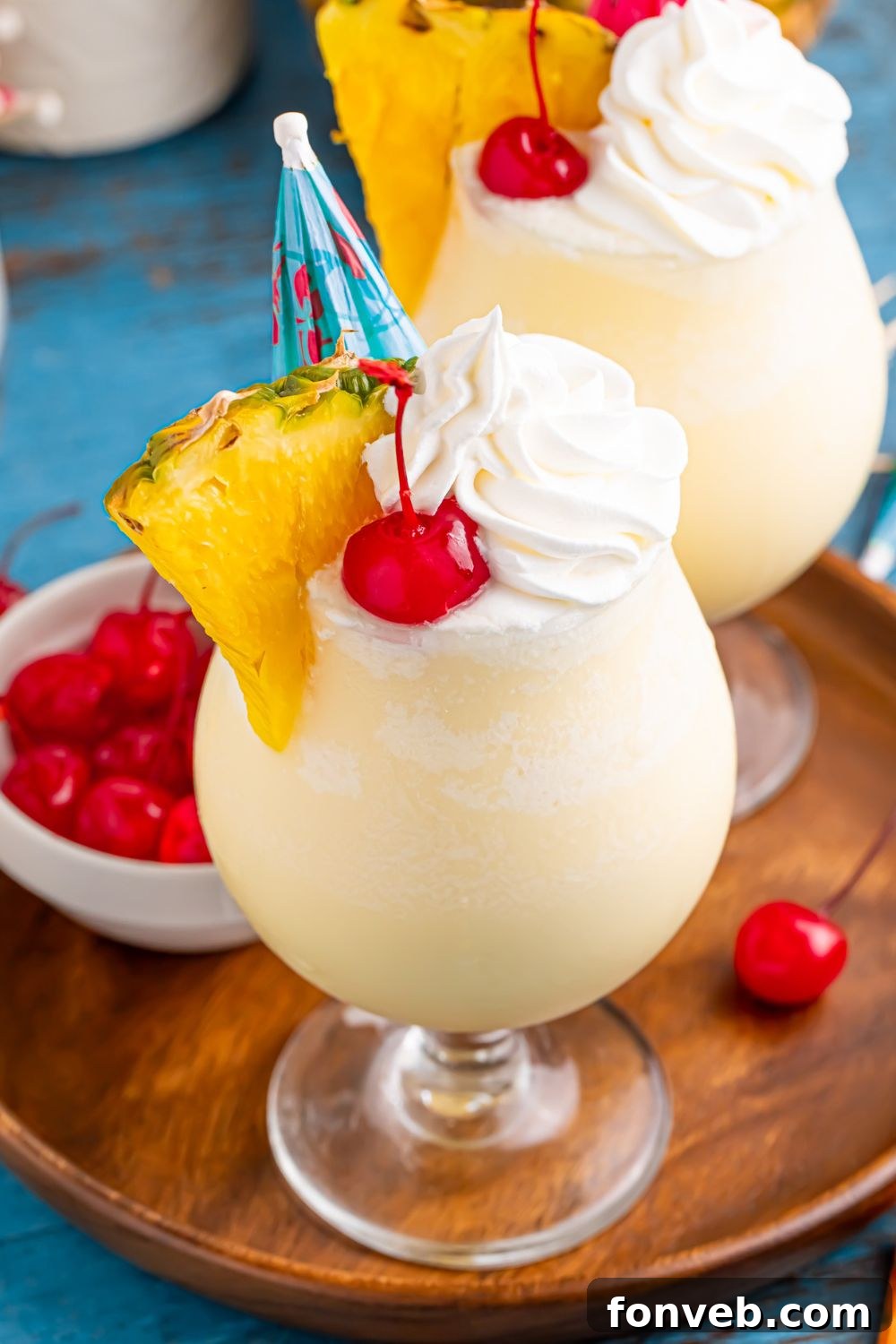 Creamy Frozen Malibu Piña Colada Delight 19 Frozen Malibu Piña Colada glasses on table with a small cocktail bowl of cherries to the side all on a tray