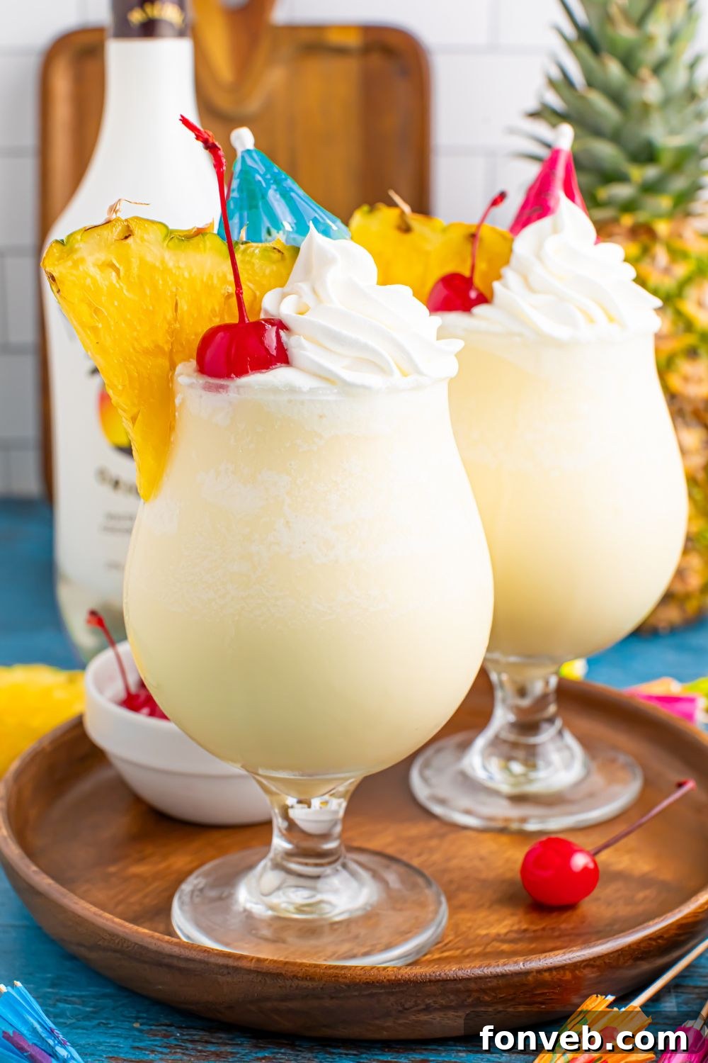 Creamy Frozen Malibu Piña Colada Delight 21 Frozen Malibu Piña Coladas on table with two drinks and a bottle of rum