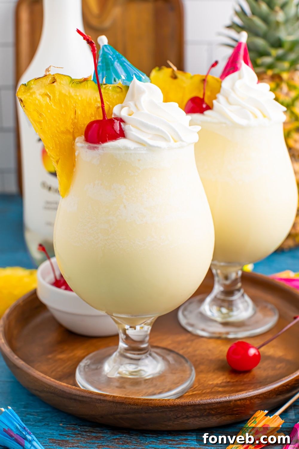 Creamy Frozen Malibu Piña Colada Delight 5 Frozen Malibu Piña Coladas in glasses on table with a bottle of malibu behind the drinks