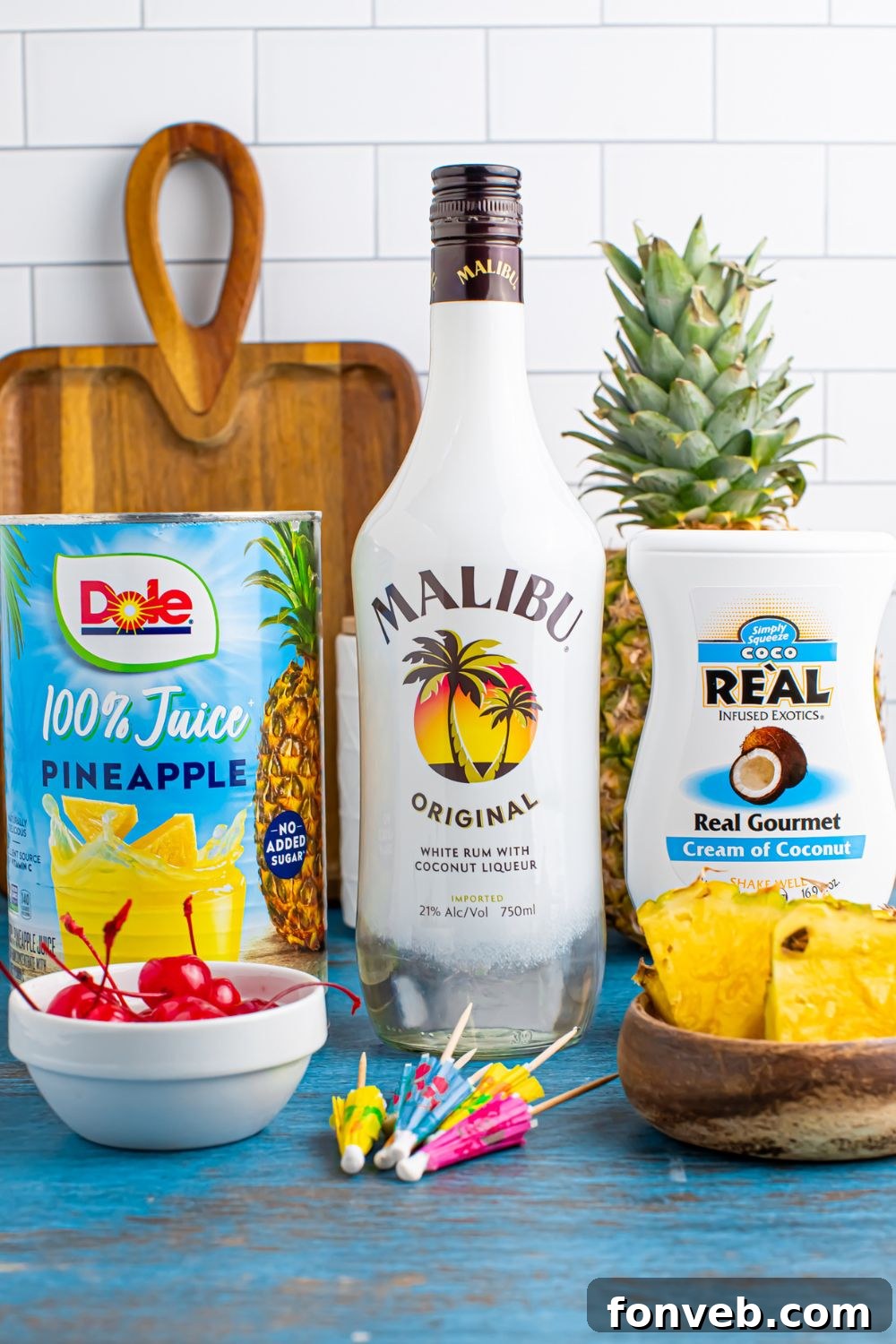 Creamy Frozen Malibu Piña Colada Delight 7 ingredients to make Frozen Malibu Piña Colada sitting on table with a cutting board sitting on table