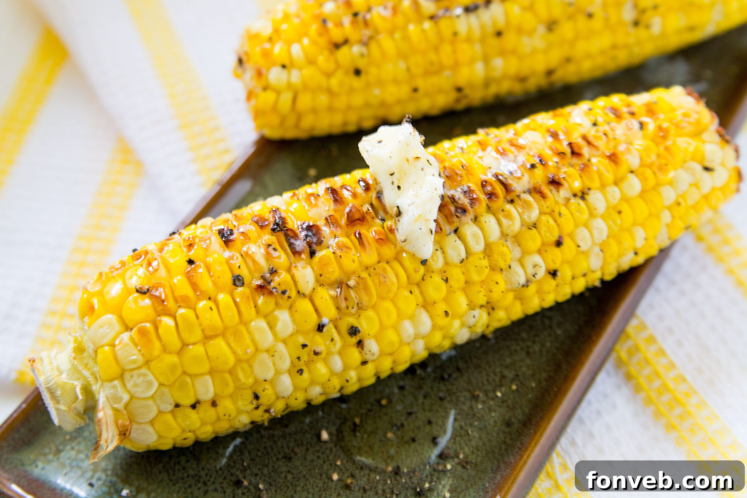 Three ears of beautifully roasted corn on the cob, seasoned and ready to eat, creating an appetizing visual.