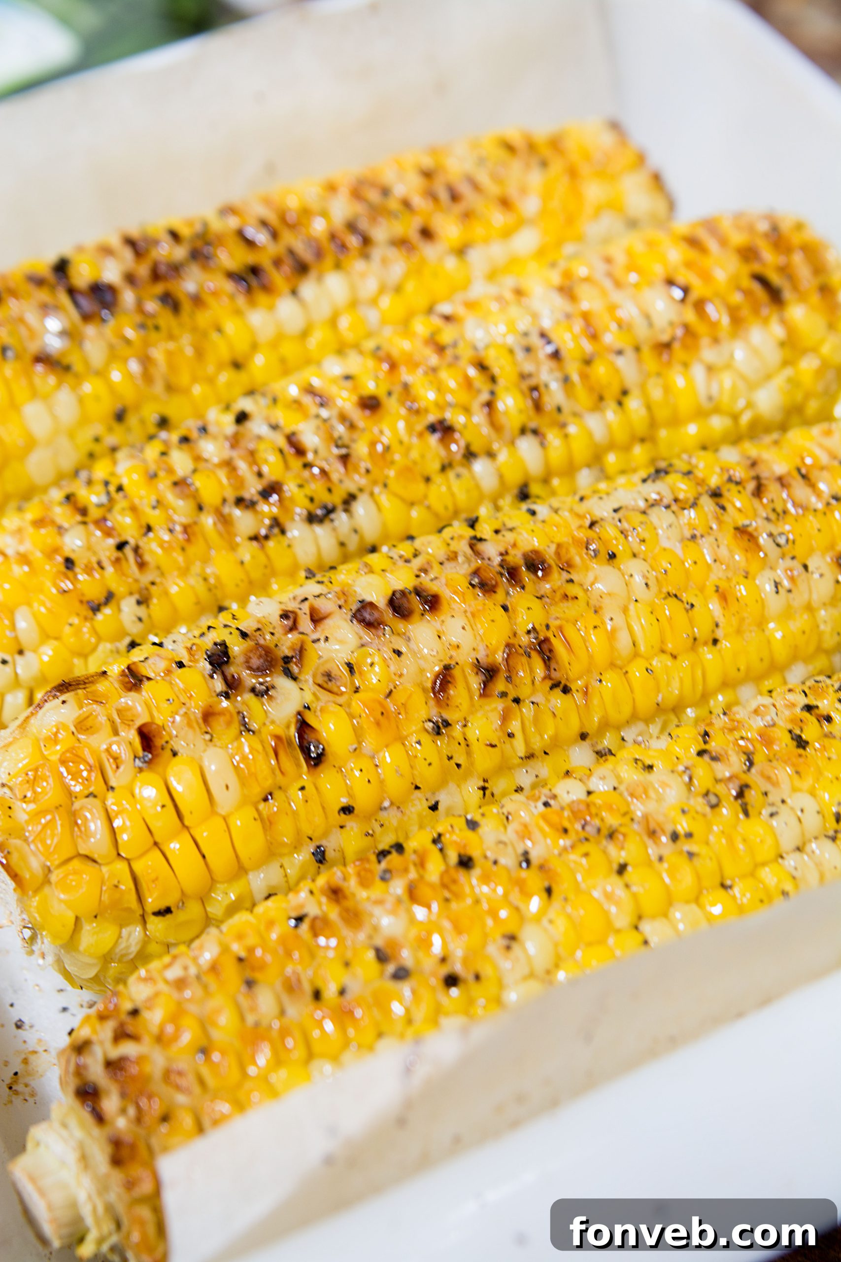 A close-up shot of a single ear of perfectly roasted corn, showing the delicious seasoning and slightly browned kernels.