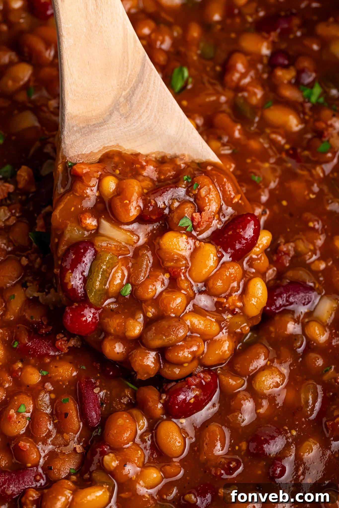 Crockpot bourbon baked beans in a bowl with a spoon scooping some out