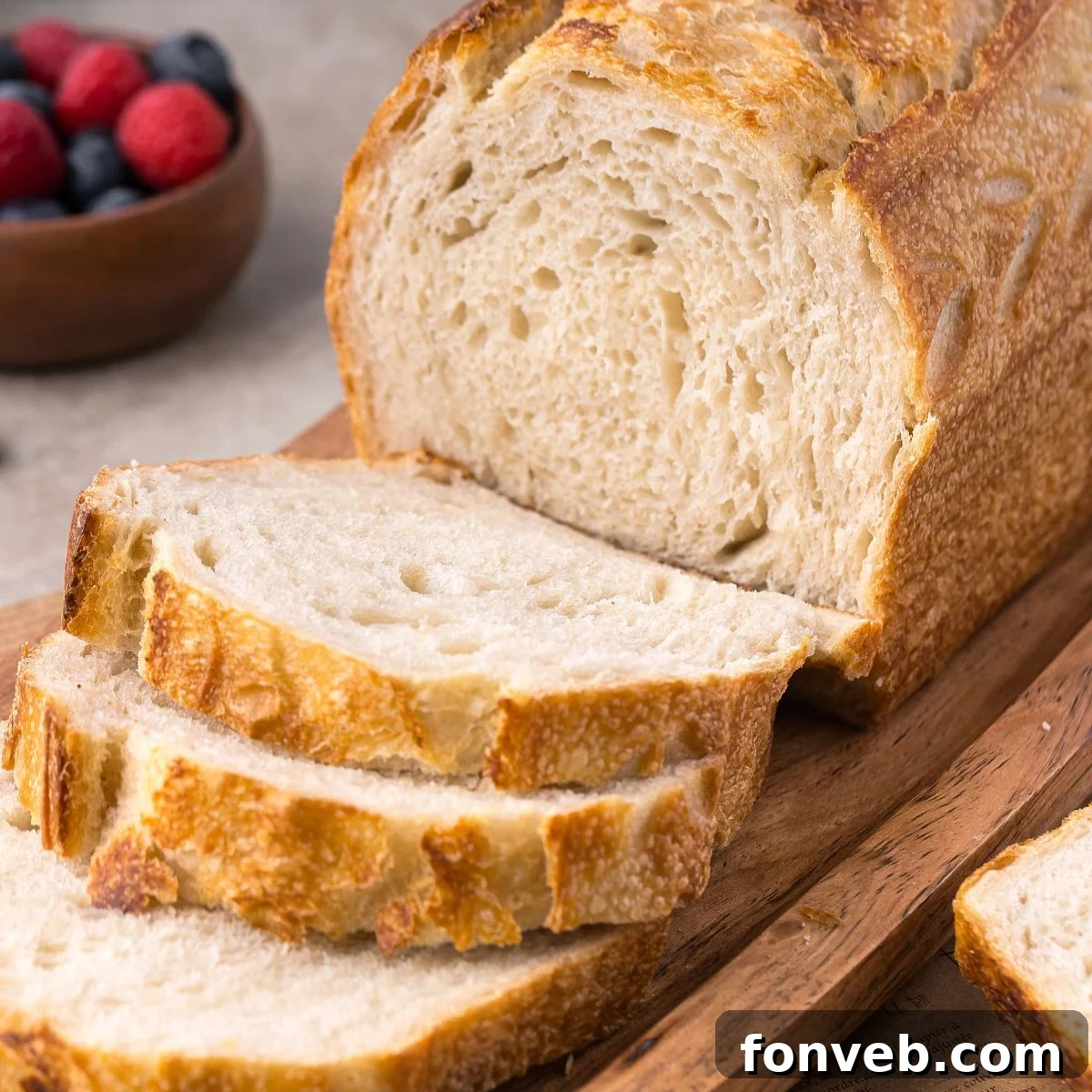 Effortless Homemade Sourdough Perfectly Crusty Always 2 Homemade Sourdough Bread on cutting board with a few slices cut out of the loaf of bread