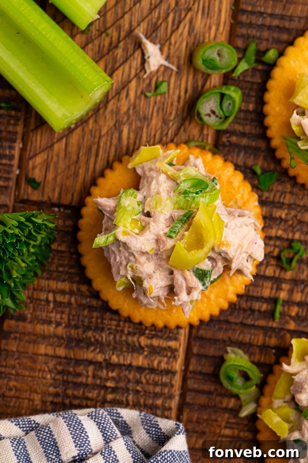 looking down at table to see celery, herbs, and a crackers with Pepperoncini Ranch Tuna Salad piled on top